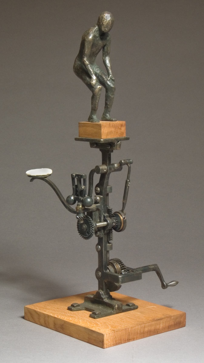 A bronze wood and steel kinetic sculpture with a nude man that is lightly tapped on the bottom with a small whote powder puff.